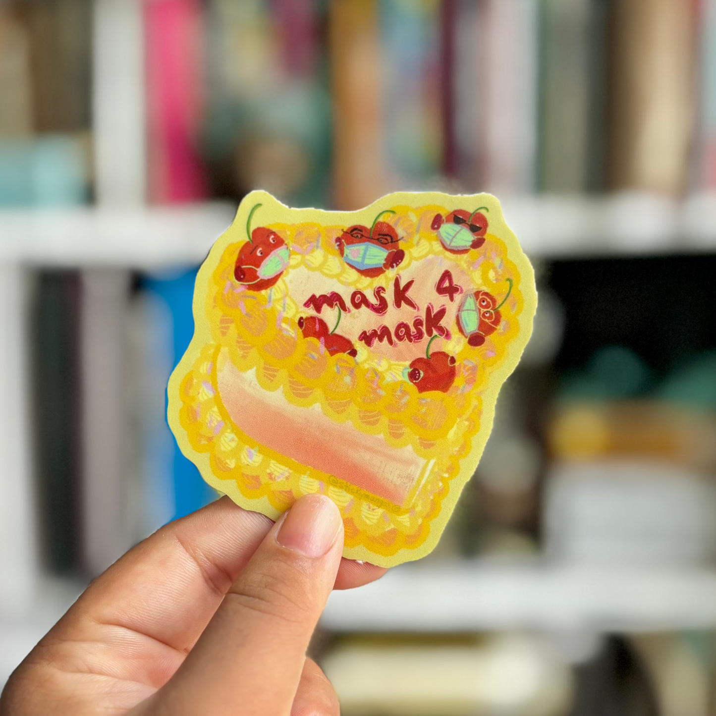 brown hand holding cake sticker. It's decorated with cherries wearing a mask, and reads 'mask 4 mask'